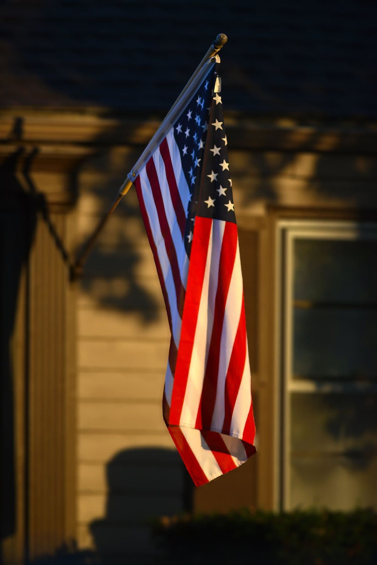 American flag hanging from a home in evening light